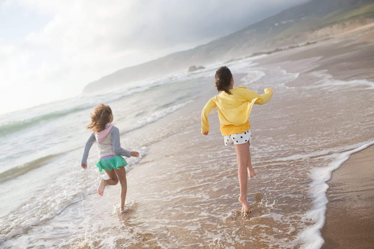 2 kids running on the beach in salento on family vacation